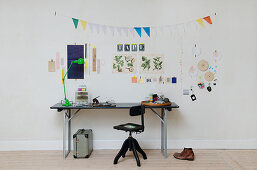 Folding table used as desk below collage and bunting on wall
