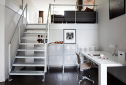 Desk with chair and metal cupboards under metal stairs in a loft apartment