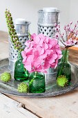 Flowers in green bottles and metal candle lanterns on vintage tray