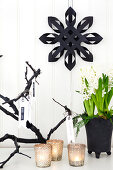 Black paper star on white wall, hyacinth and votive candles lit