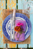 Napkin decorated with French marigold, phlox and verbena flowers on old plate
