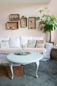 Round coffee table in front of sofa with lacy blanket and vintage-style accessories in living room