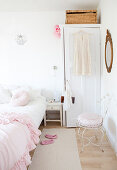 Rosafarbene Rüschendecke auf dem Bett, Schrank und Stuhl im Schlafzimmer in Weiß