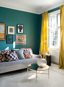 Picture gallery above the sofa in the living room with petrol blue walls