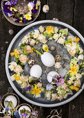 Wreath of roses, daffodils, viburnum, and grape hyacinths on a tray