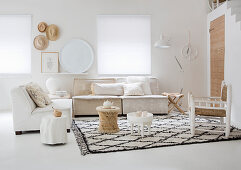 A side table on a diamond patterned rug with sofas in a light living room