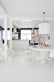 Round table with various chairs in front of the kitchen island and stairs in a white, open living room