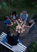 Children around a round garden table with homemade lanterns