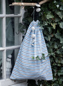 A homemade sack made of striped fabric hanging from the window
