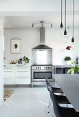 A view next to a dining area of a kitchenette with a gas cooker and an extractor fan