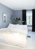 A double bed and black curtains in a blue-grey bedroom