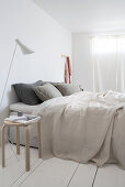 A double bed in a minimalist bedroom with white floorboards