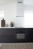 A dark kitchen unit with an extractor fan next to window