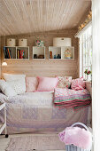 A cosy day bed in a small room with panelled walls and ceiling