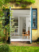 A view through open double doors from a garden into a living room