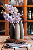 Three vases of flowers with a china cabinet in the background