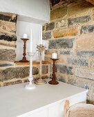Candlesticks on low sideboard in rustic niche