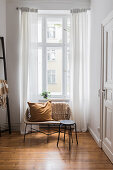 Cushion on bench and stool in front of tall period-apartment windows