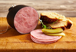 Tyrolean ham, sliced with gherkin and bread on a wooden surface