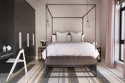 Modern four-poster bed in bedroom in shades of grey