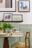 Small dining table and chair next to wall with pictures above wainscoting