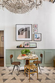 Small dining table and chairs next to wall with pictures above wainscoting
