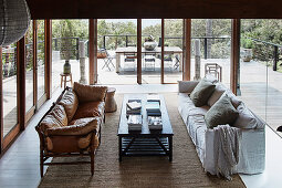 Leather sofa and slipcover sofa around coffee table in lounge with all-round glazing