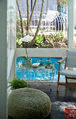 View from living room with black-painted tiled floor onto terrace with pool