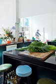 Bar stools at dark counter with large leaves on wooden board