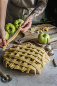 Preparing apple pie, decorating the mold with cake stripes