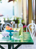 Kalter Weißwein im Glas und in der Flasche auf grünem Tisch