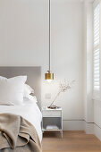 Golden pendant lamp above bedside table in bedroom