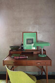 Green table lamp and picture on desk against grey wall