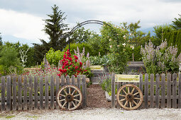 Old wagon wheels flanking entrance to garden below rose arch