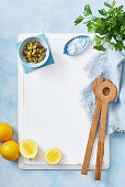 Pistazien, Zitronen, Salz und Salatbesteck auf Schneidebrett