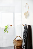 Towels hung from hooks and basket below extravagant necklace hung on wall