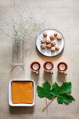 Napkins in bowl, vine leaves, tealights, walnuts and flowering twigs in glass vase