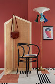 DIY-Paravent aus Wiener Geflecht, Stuhl und Stehlampe vor rot gestrichener Wand