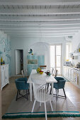 Dining area in white country-house kitchen with wood-beamed ceiling