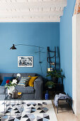 Grey sofa in living room with blue wall and white wood-beamed ceiling
