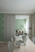 Artistic bowls on long dining table with classic chairs in front of sliding doors leading into lounge