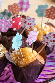 Muffins decorated with handmade paper flowers on toothpicks