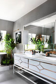 Twin sinks and numerous houseplants in glamorous bathroom