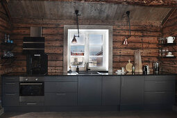 Modern fitted kitchen with grey fronts in rustic wooden cabin