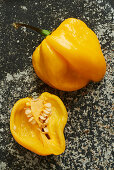 One whole and one halved yellow Habanero chilli pepper