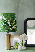 Table lamp with leaf motif, Chinese money plant and small sculpture in front of mirror