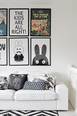 Scatter cushions on white sofa below gallery of comic art