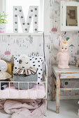 Decorative letter on windowsill above dolls' bed in child's bedroom in shades of grey