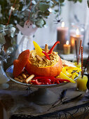 Halloween-Kürbis mit Hummusfüllung und Gemüsesticks