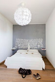 Minimalistisches Schlafzimmer mit weißem Bett und Lebensbaum-Motiv an grauer Wand